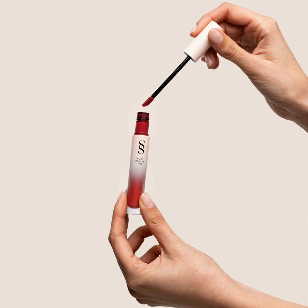 Femme appliquant le rouge à lèvres Sensilis ETERNALIST A.G.E avec applicateur liquide.