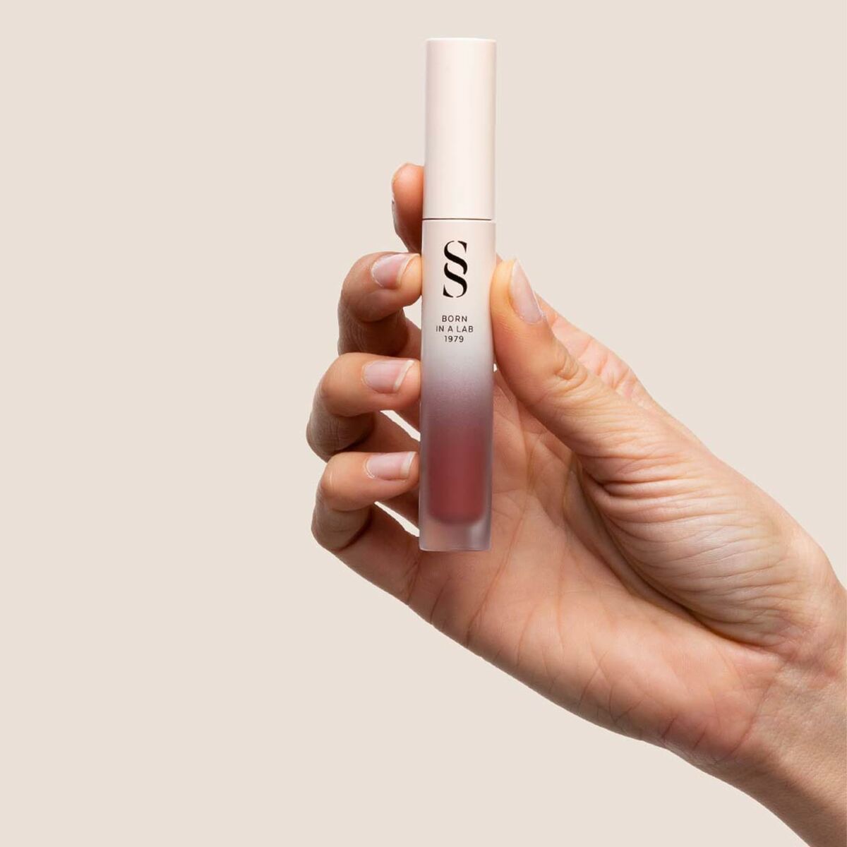 Main hand holding Rouge à lèvres Sensilis ETERNALIST A.G.E Beige 4.5 ml in stylish packaging.