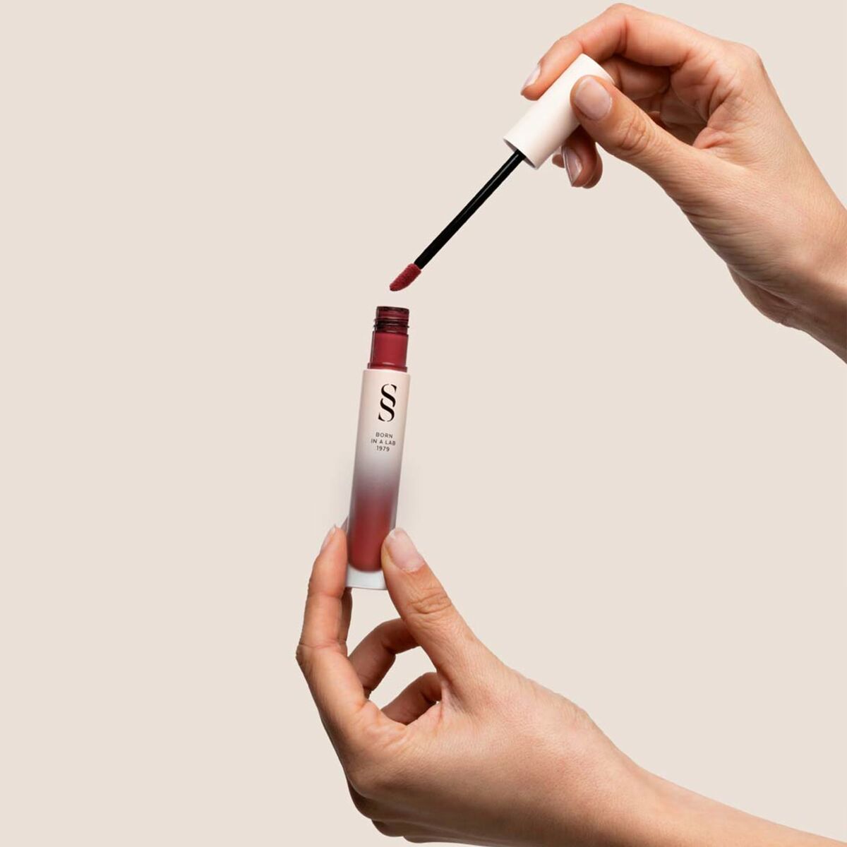 Application of Sensilis ETERNALIST A.G.E Beige liquid lipstick in hands with applicator.