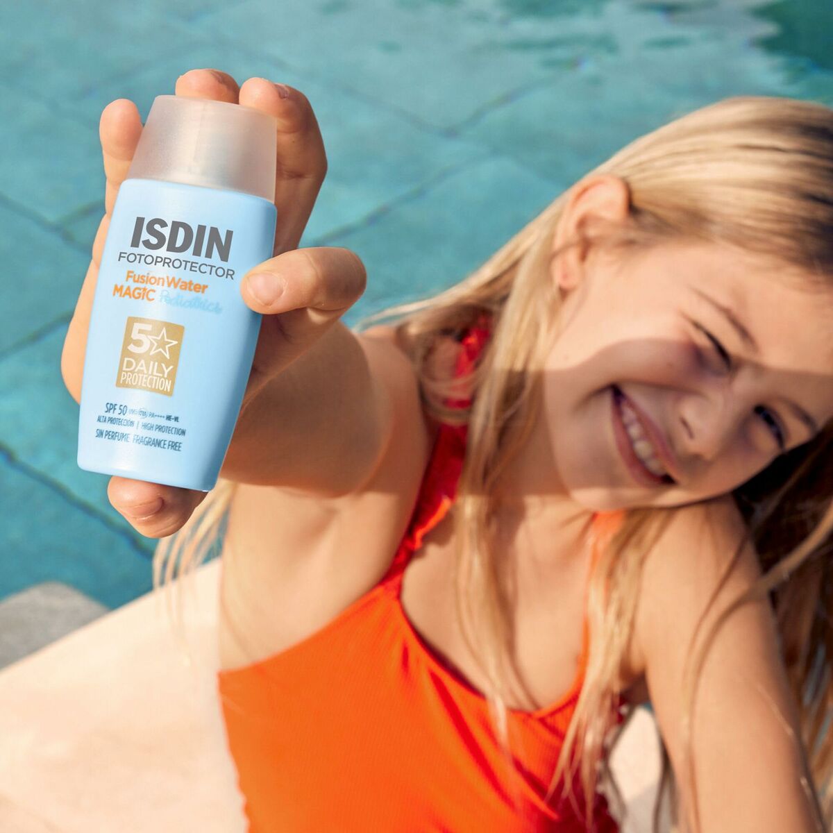 A child holding ISDIN Fotoprotector Magic Water sunscreen bottle by the pool, showcasing sun protection skincare.