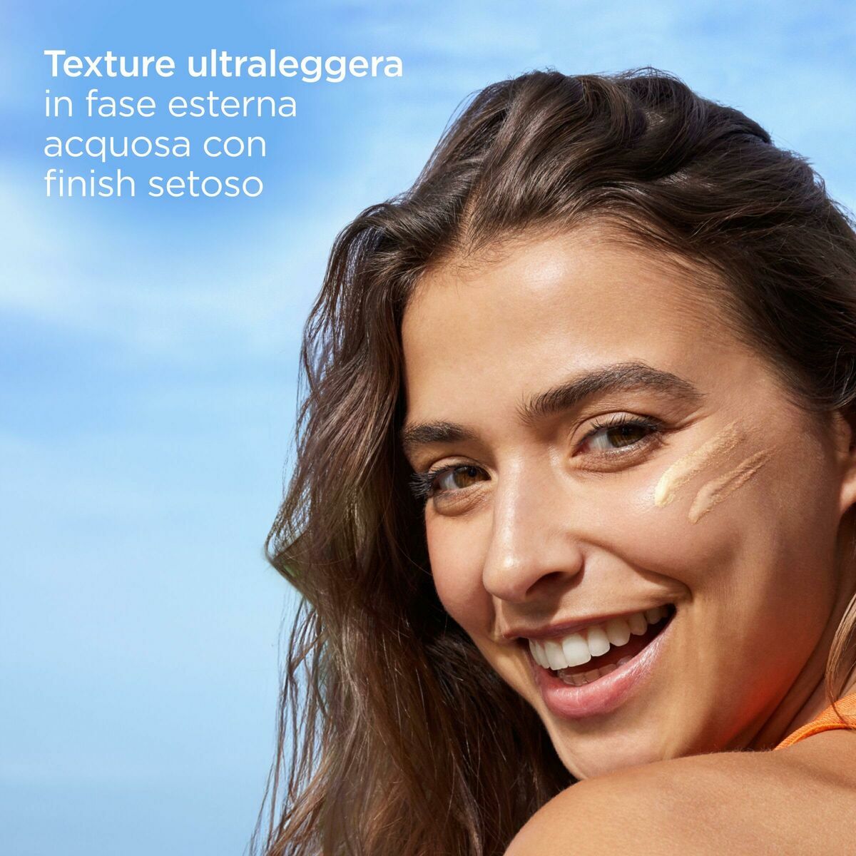 Femme souriante montrant la texture légère et soyeuse du protecteur solaire sur sa peau.