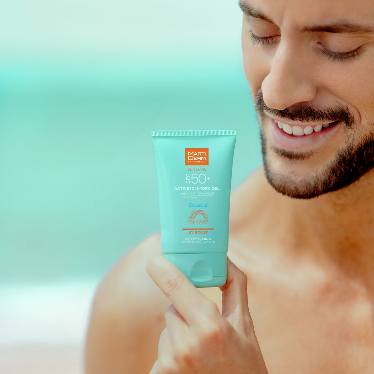 Homme tenant le Protecteur Solaire Martiderm SUN CARE SPF 50+, produit en tube de 50 ml sur une plage.