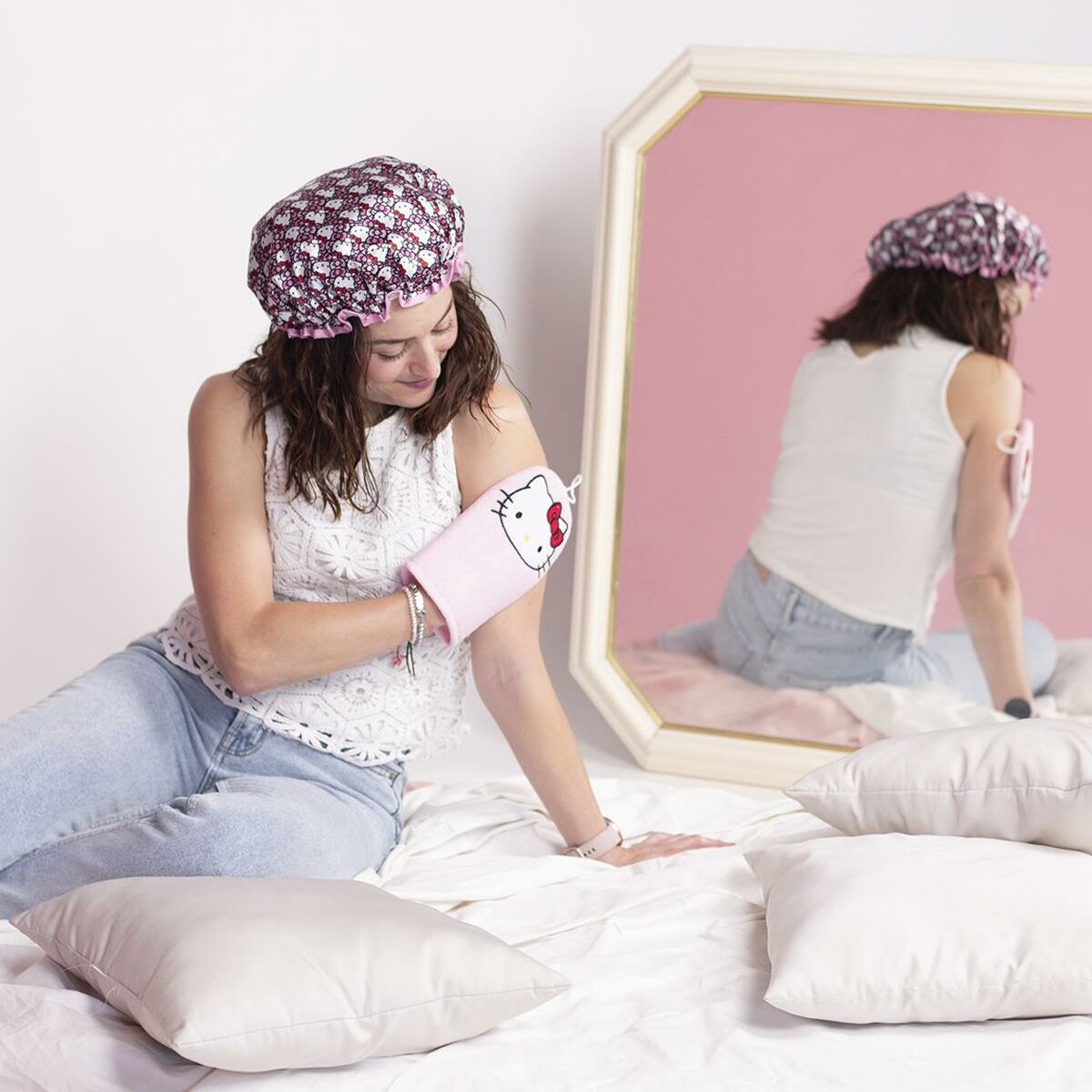 Femme portant un bonnet de douche Hello Kitty rose en polyester, assise sur un lit avec des coussins.