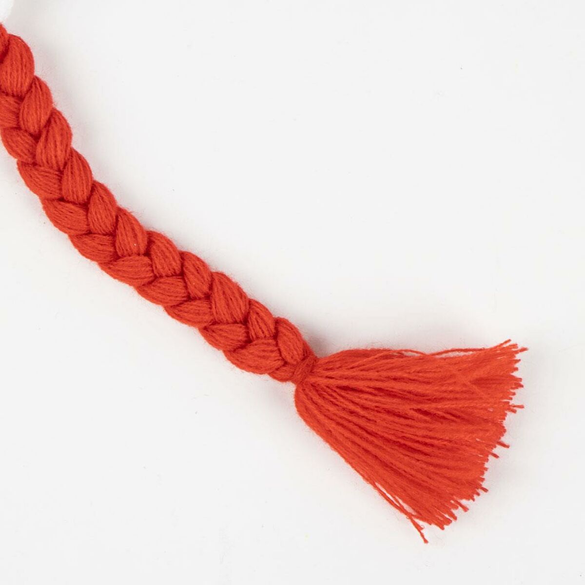 Close-up of a braided orange yarn tassel with a tufted end, ideal for crafts or decorative purposes.