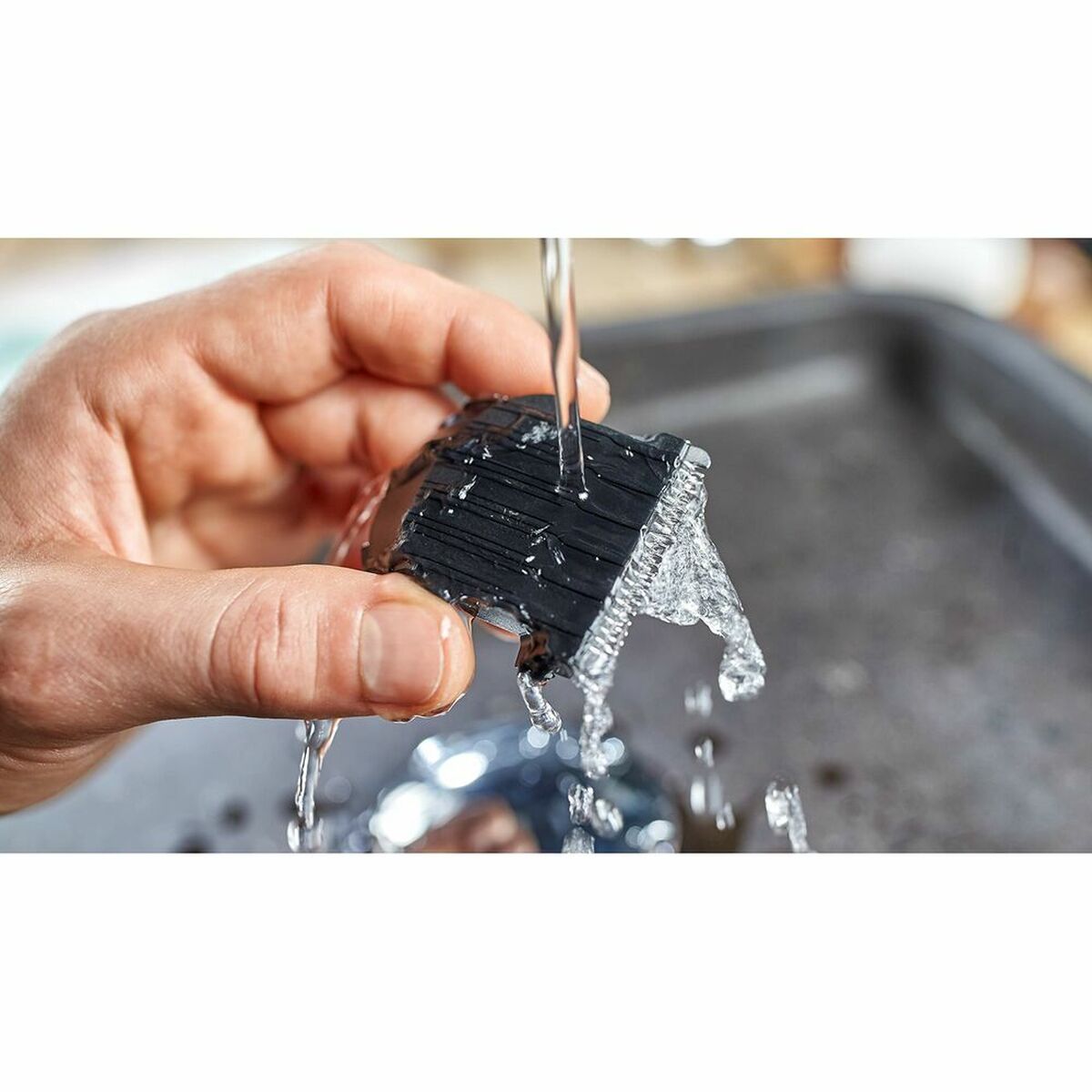 Person holding a washable Philips series 3000 grooming blade under running water, showcasing its easy cleaning feature.
