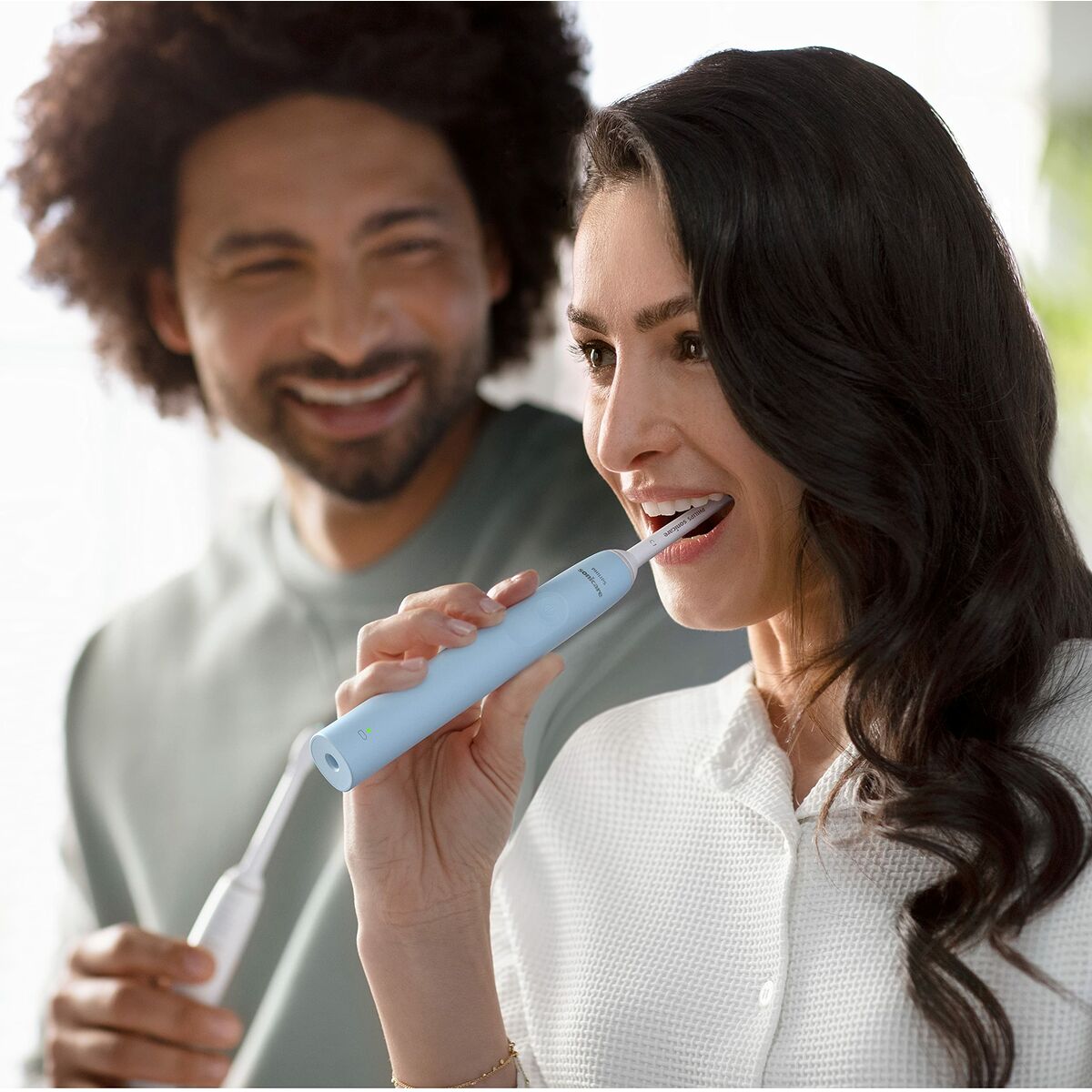Person using Philips electric toothbrush, promoting oral hygiene with a smile.