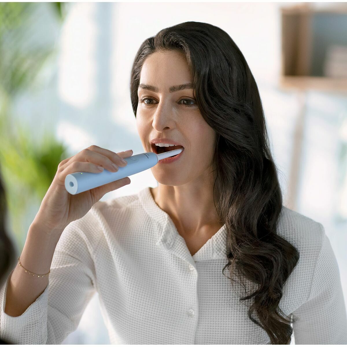 Femme utilisant une brosse à dents électrique Philips pour améliorer son hygiène buccale.