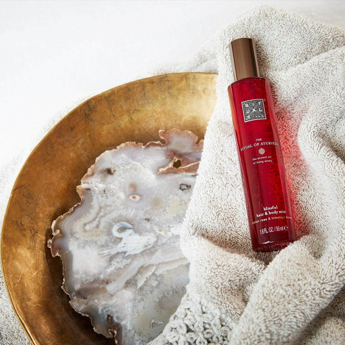 Parfum Corporel Rituals The Ritual of Ayurveda 50 ml on a soft towel next to a decorative bowl.