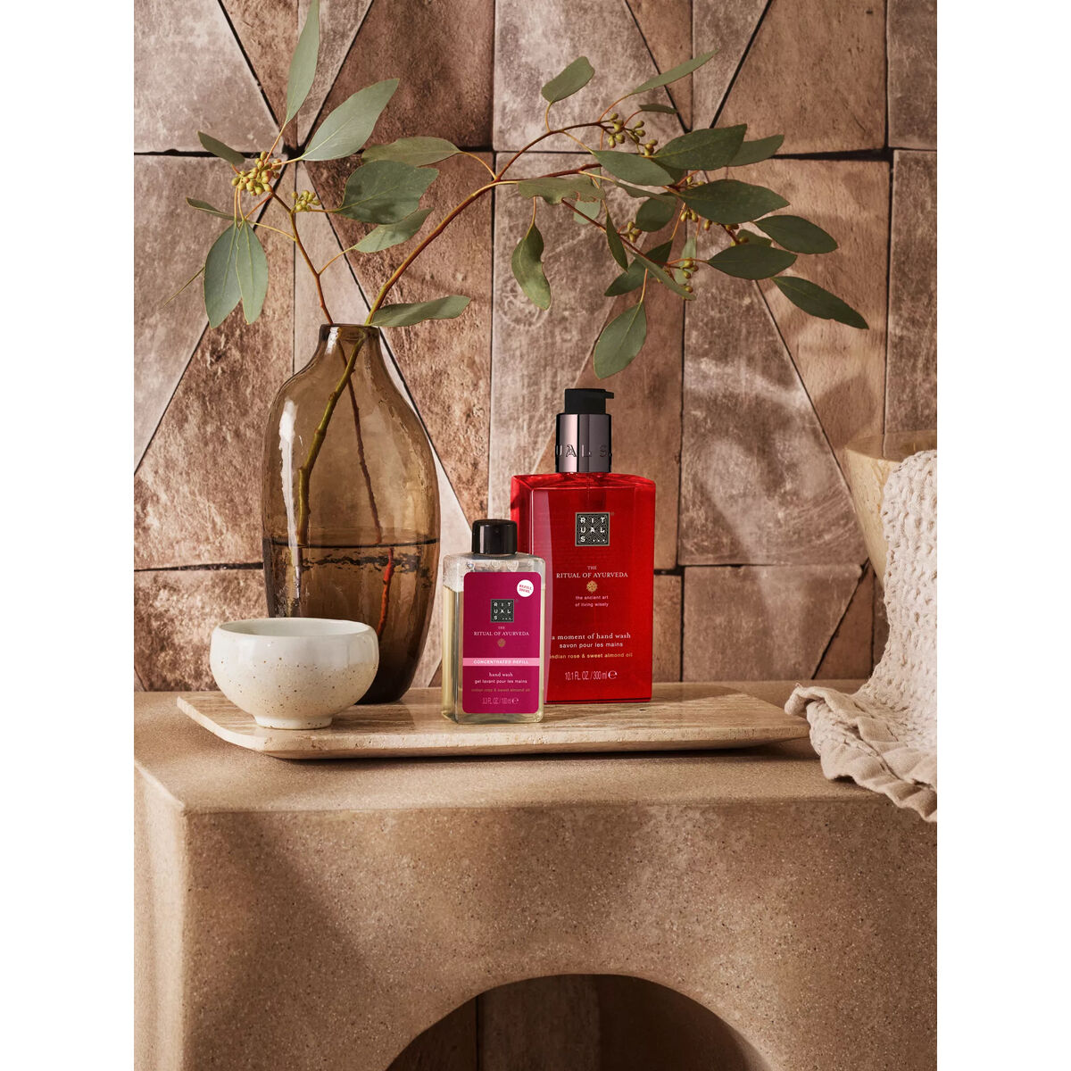 Rituals THE RITUAL OF AYURVEDA gel de douche packaging displayed on a stylish stone surface with greenery.