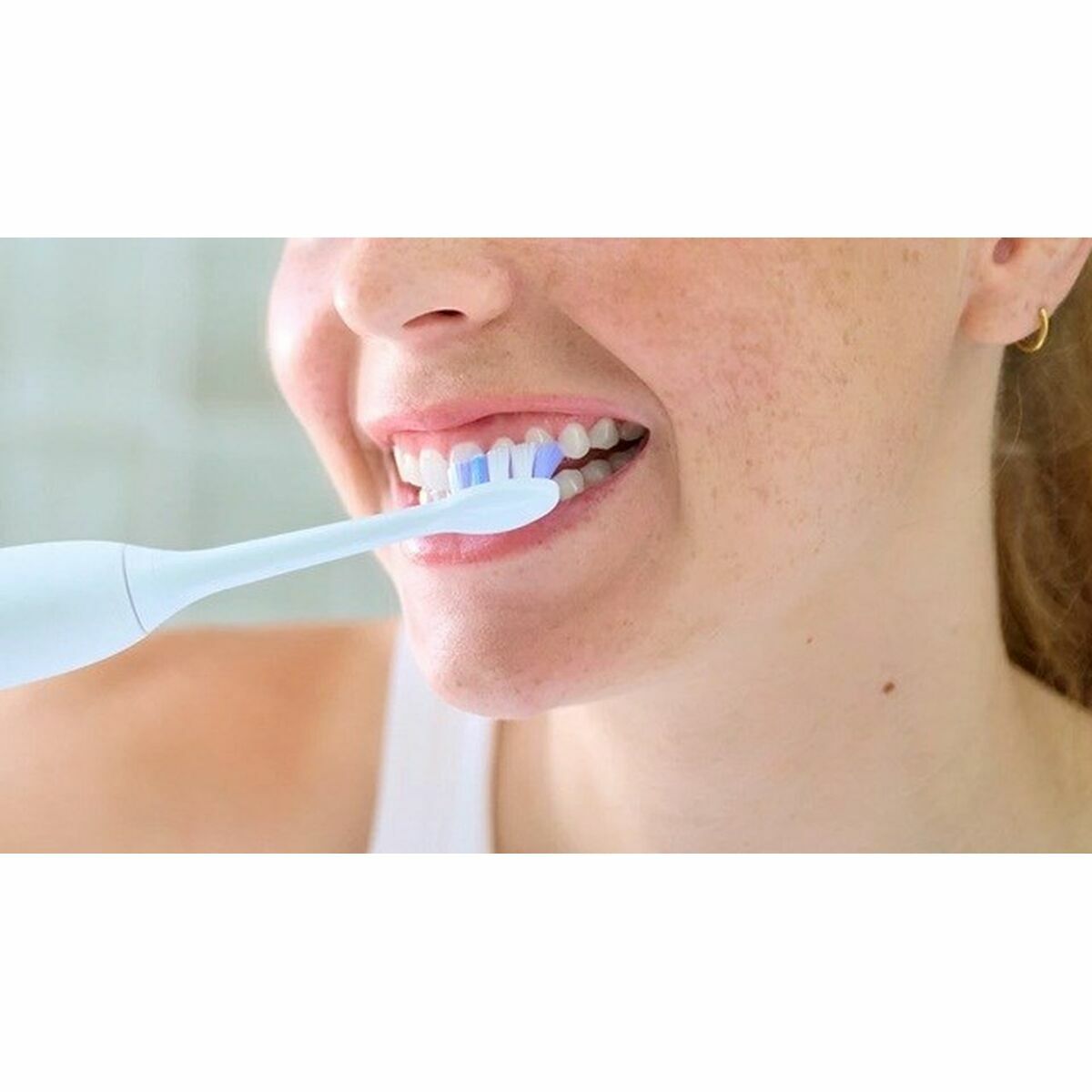 Woman using Philips HX6052/87 replacement toothbrush head for improved oral hygiene.